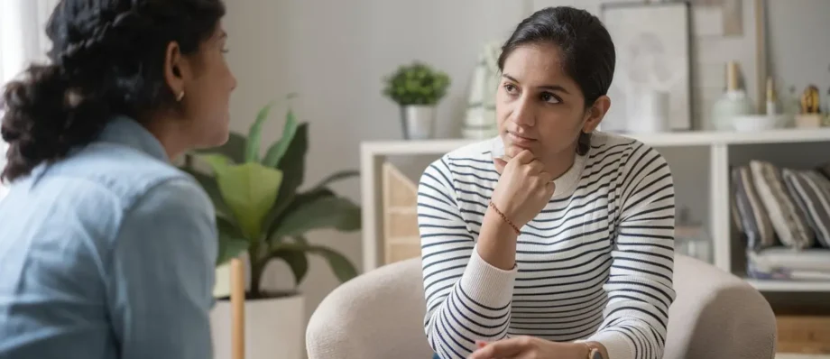“Two Indian women seated in a calm, indoor setting, with one appearing to provide professional counseling to the other.”